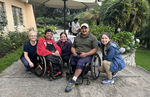 Dr. Tsotsoros with two colleagues and two people in wheelchairs.