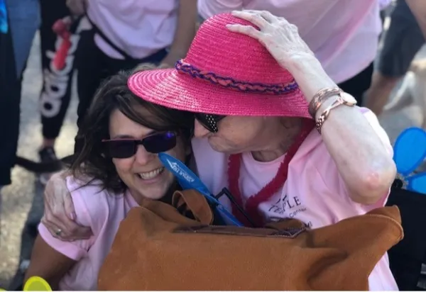 A resident wearing a pink hat hugs Patty.